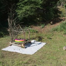 Landartbühne mit Baumhaut in Planschbecken auf Brennnessel gebettet, eine Kunstinstallation von Martin Gut, 2023
